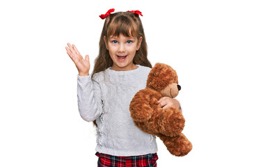 Little caucasian girl kid hugging teddy bear stuffed animal celebrating victory with happy smile...