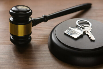 Real estate law and house auction concept. Selective focus of key with house keychain and gavel on...