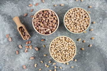 Bowls of various uncooked beans on marble surface