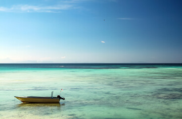 Motor boat standing on shallow water, bright blue sky and turquoise sea water