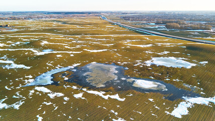 Spring fields aerial view. Snow melting, water pools on meadows. Season change.