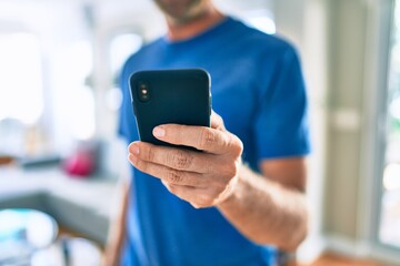 Young irish man smiling happy using smartphone standing at home.