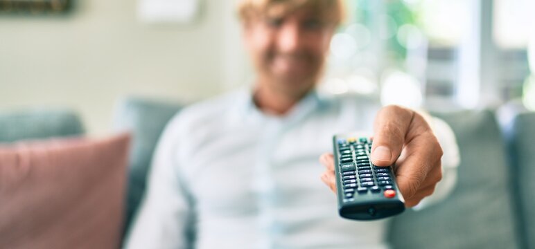 Close up of middle age handsome caucasian man using tv control