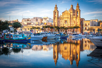 Obraz premium malta, big church at sunset in front of a port with reflection