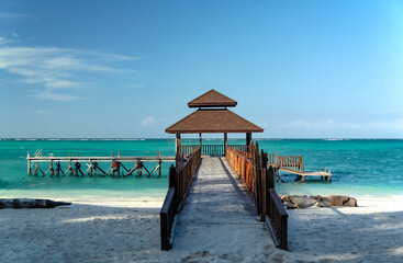 Wooden pier near sandy beach on turquoise sea background