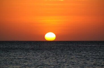 warm sunset over seawater, sun touching seawater on the horizon