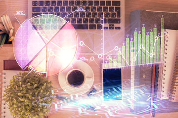 Double exposure of financial graph hologram over desktop with phone. Top view. Mobile trade platform concept.