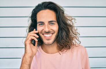 Young hispanic man smiling happy talking on the smartphone at city.