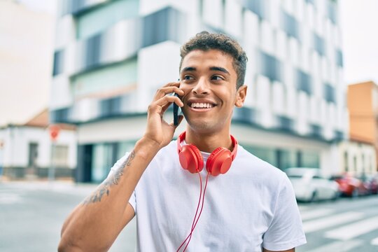 Young latin man smiling happy talking on the smartphone and using headphones at the city.