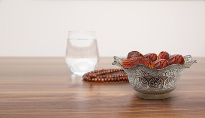 Typical of the month of Ramadan for muslims is the setting here, after the fast has been broken - water and pitted dates. Traditional iftar food.
metal bowl full of date fruits symbolizing Ramadan