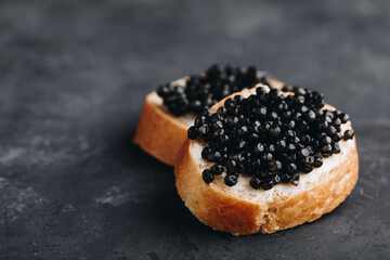 Black caviar sandwiches with butter on dark background