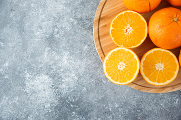 A wooden board full of juicy slices of orange fruit on stone background