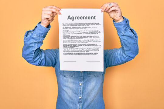 Woman holding agreement document paper standing over isolated yellow background