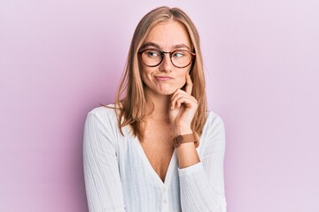 Beautiful blonde woman wearing casual clothes and glasses thinking concentrated about doubt with...
