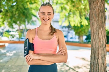 Fototapeta premium Young blonde sportswoman using earphones doing exercise at the park
