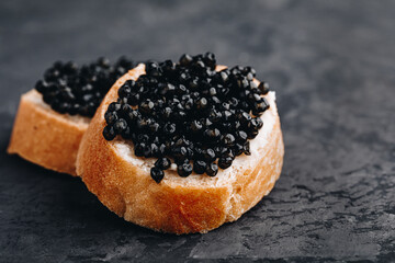 Black caviar sandwiches with butter on dark background