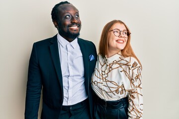 Young interracial couple wearing business and elegant clothes smiling looking to the side and staring away thinking.