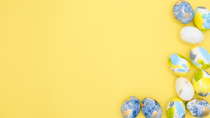 Top view of easter holiday yellow backdrop with creative eggs decorations in trendy blue, gray, golden colors. Flat lay colorful composition with copy-paste for text for postcard, banner, invitation