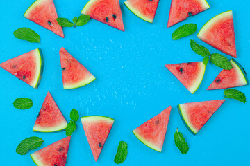 Top view, sliced watermelon fruit with many mints leaves on the old blue wooden table for background, wallpaper, and backdrop