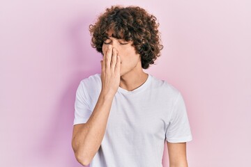 Handsome young man wearing casual white t shirt bored yawning tired covering mouth with hand. restless and sleepiness.