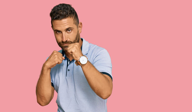 Handsome man with beard wearing casual clothes ready to fight with fist defense gesture, angry and upset face, afraid of problem