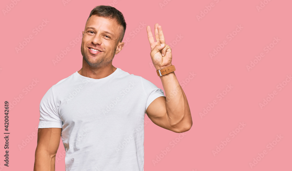 Canvas Prints Handsome muscle man wearing casual white tshirt showing and pointing up with fingers number three while smiling confident and happy.