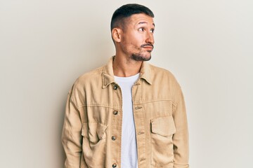 Obraz premium Handsome man with tattoos wearing casual brown denim jacket smiling looking to the side and staring away thinking.