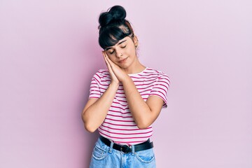 Young hispanic girl wearing casual clothes sleeping tired dreaming and posing with hands together while smiling with closed eyes.