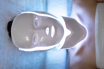 LED mask regenerative treatment applied to a young woman. Woman with led light therapy facial and...