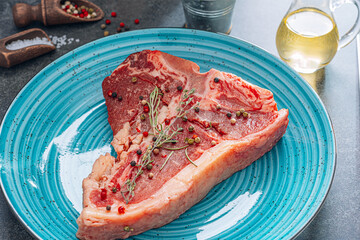 fresh and raw t-bone steak in a blue plate on a stone background