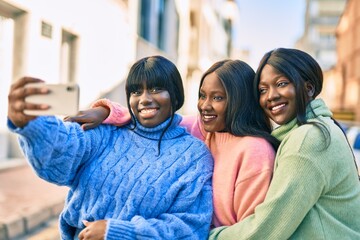 Three african american friends smiling happy making selfie by the smartphone at the city.