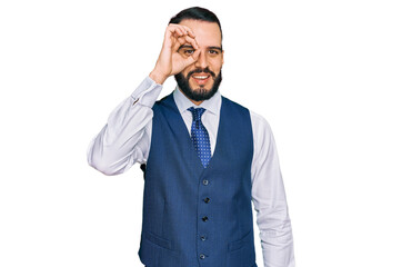 Young man with beard wearing business vest doing ok gesture with hand smiling, eye looking through fingers with happy face.