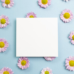 Blank memo pad with pink small flowered chrysanthemum on sky blue background. floral decoration. flat lay, top view, copy space