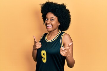 Young african american woman wearing basketball uniform pointing fingers to camera with happy and...