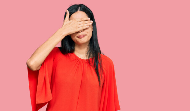 Beautiful young woman wearing casual clothes covering eyes with hand, looking serious and sad. sightless, hiding and rejection concept