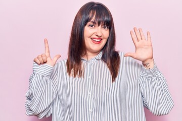 Young plus size woman wearing casual clothes showing and pointing up with fingers number seven while smiling confident and happy.