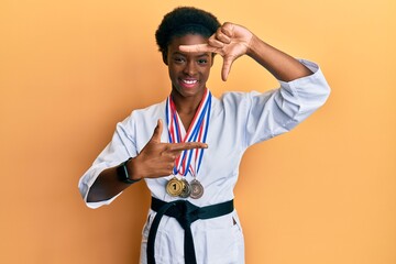 Young african american girl wearing karate kimono and black belt smiling making frame with hands...