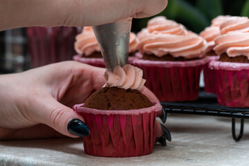 The confectioner decorates with a delicately pink cream of cupcakes in pink moulds.