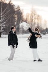 Young couple playing with snow in winter park