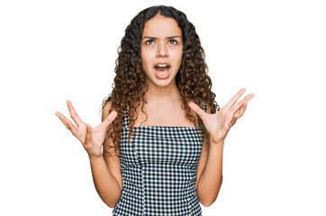 Teenager hispanic girl wearing casual clothes crazy and mad shouting and yelling with aggressive...