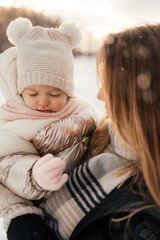 Young mom holding small beautiful baby girl in winter hat