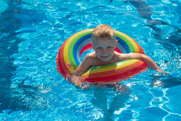 Caucasian boy swims in the summer pool on an inflatable circle