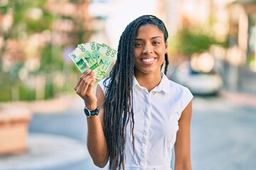 Young african american woman smiling happy holding norwegian 50 krona banknotes at the city.