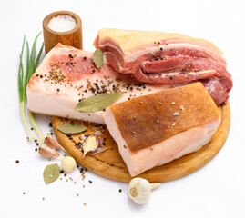 raw pork meat and lard with salt, spices and garlic on a cutting board, white background