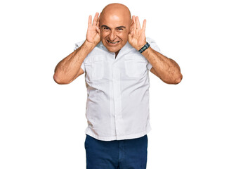 Fototapeta premium Mature middle east man with mustache wearing casual white shirt trying to hear both hands on ear gesture, curious for gossip. hearing problem, deaf