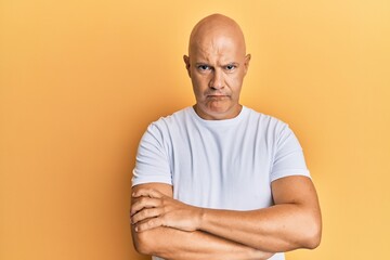 Middle age bald man wearing casual white tshirt skeptic and nervous, disapproving expression on...