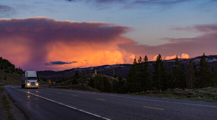 Beautiful red sunset over the mountains, car on the road. US