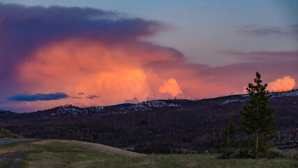 Obraz premium A beautiful red sunset over the mountains overgrown with coniferous forest. US