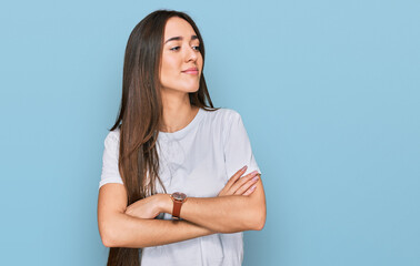 Obraz premium Young hispanic girl wearing casual white t shirt looking to the side with arms crossed convinced and confident