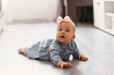 Baby girl learns to crawl on the floor in the room.